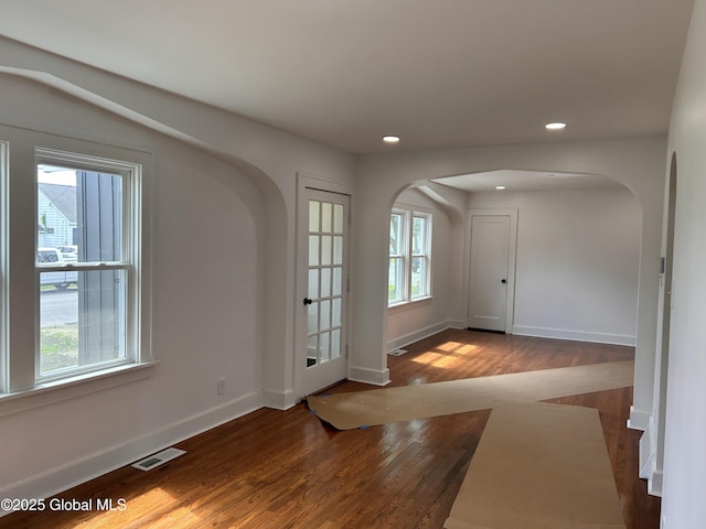 foyer with arched walkways, baseboards, wood finished floors, and recessed lighting