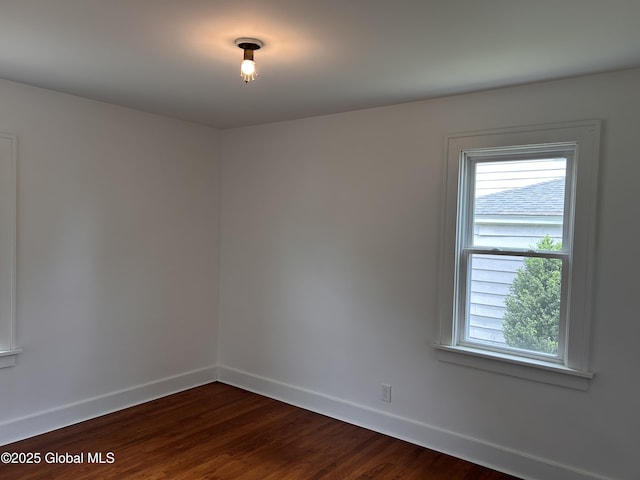 unfurnished room with baseboards and dark wood-style floors