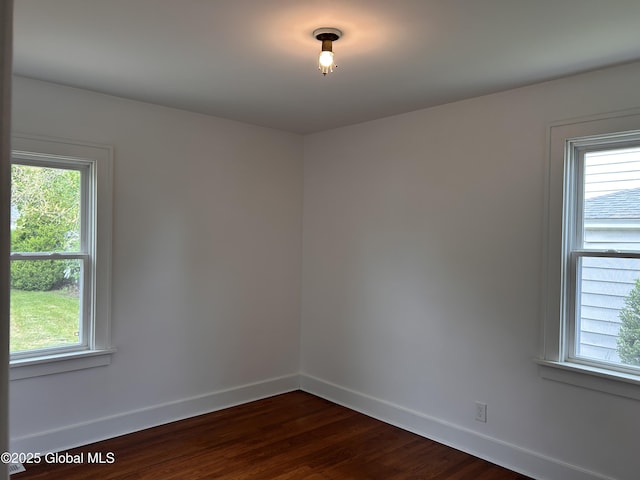 unfurnished room with baseboards, plenty of natural light, and dark wood-style floors