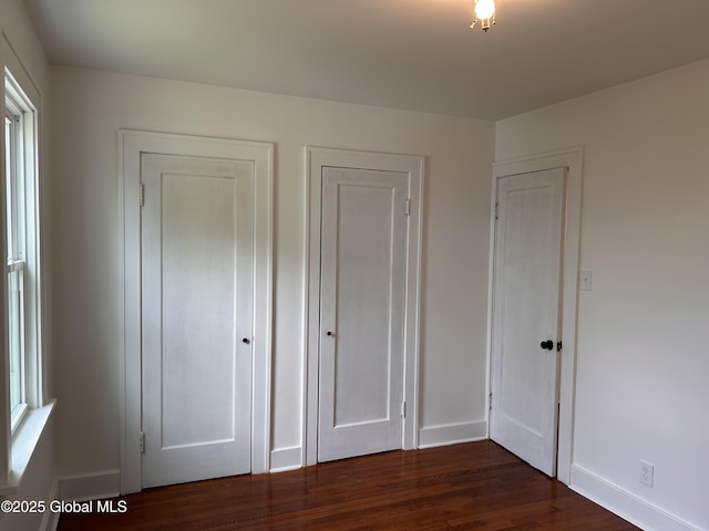 unfurnished bedroom with baseboards and dark wood finished floors