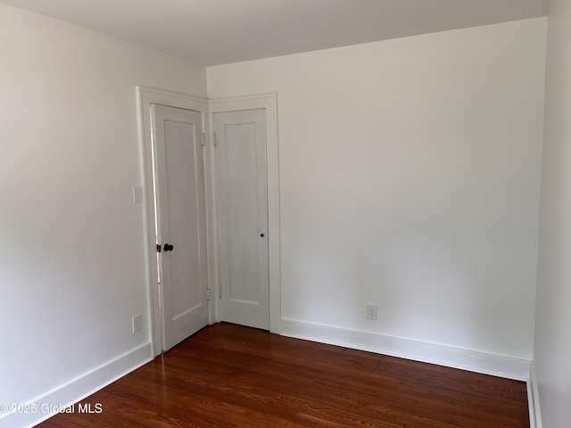 empty room with baseboards and dark wood-style flooring