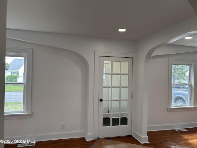 doorway to outside featuring arched walkways, healthy amount of natural light, baseboards, and recessed lighting