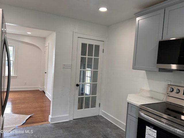 kitchen featuring electric range oven, stainless steel microwave, gray cabinets, baseboards, and light stone countertops