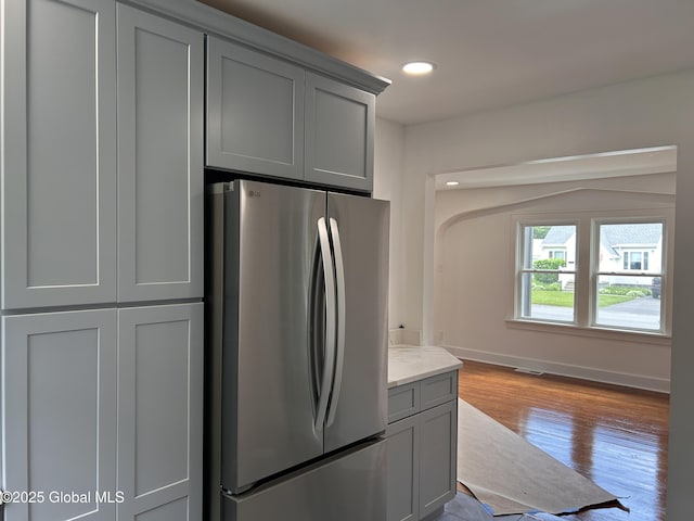 kitchen featuring freestanding refrigerator, gray cabinetry, wood finished floors, baseboards, and recessed lighting