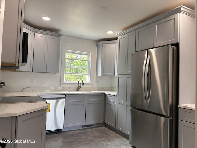 kitchen with appliances with stainless steel finishes, gray cabinetry, a sink, light stone counters, and recessed lighting