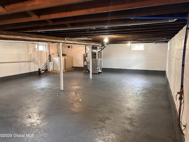 below grade area with washer and clothes dryer, heating unit, and electric water heater