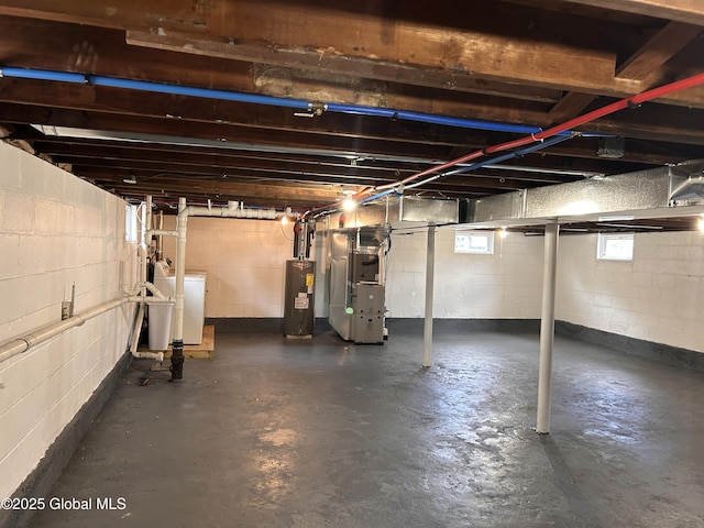 basement featuring water heater, heating unit, and washer and clothes dryer