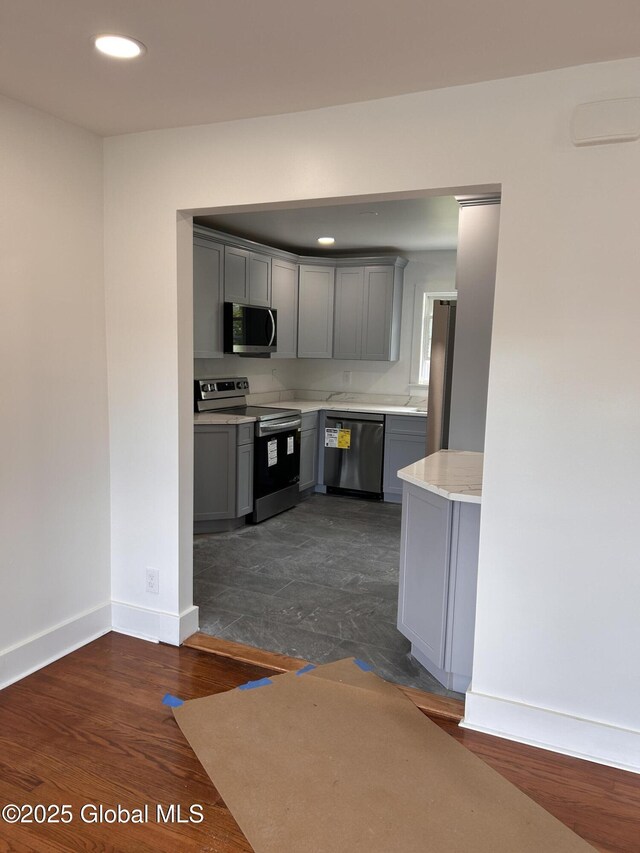 kitchen featuring stainless steel appliances, gray cabinets, light countertops, baseboards, and recessed lighting