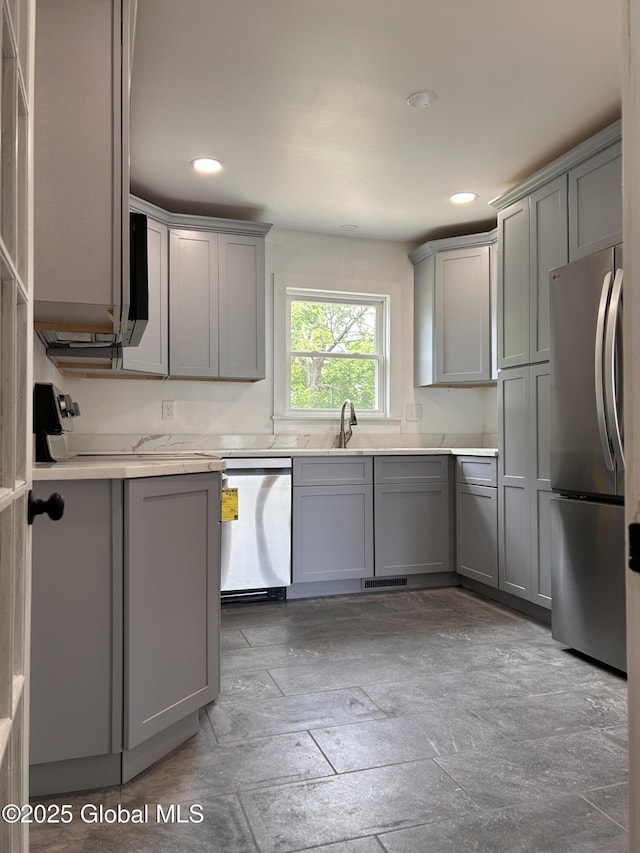 kitchen featuring appliances with stainless steel finishes, gray cabinets, light countertops, recessed lighting, and a sink