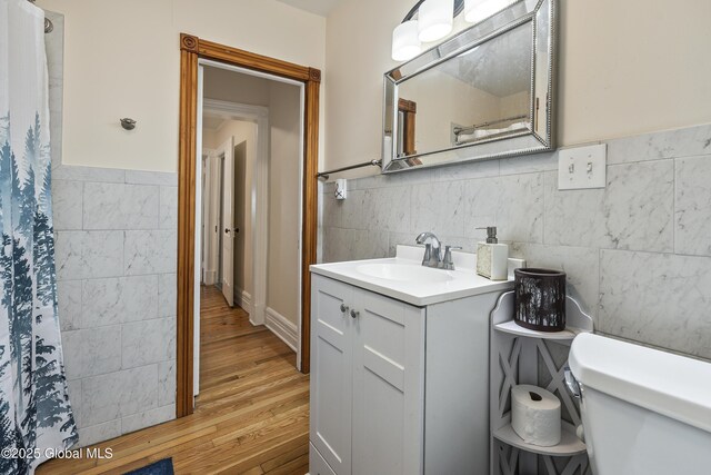 1409 Indian Fields Rd, Bethlehem, NY 12067 - full bathroom featuring tile walls, wood finished floors, toilet, vanity, and a wainscoted wall