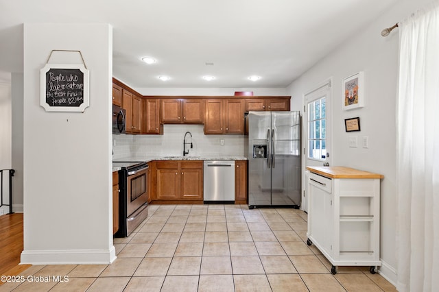 7 Hathorn Blvd, Saratoga Springs, NY 12866 - kitchen featuring appliances with stainless steel finishes, tasteful backsplash, brown cabinets, and light tile patterned floors