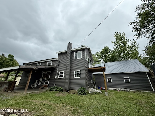 rear view of property with a yard, a chimney, a patio, a balcony, and entry steps