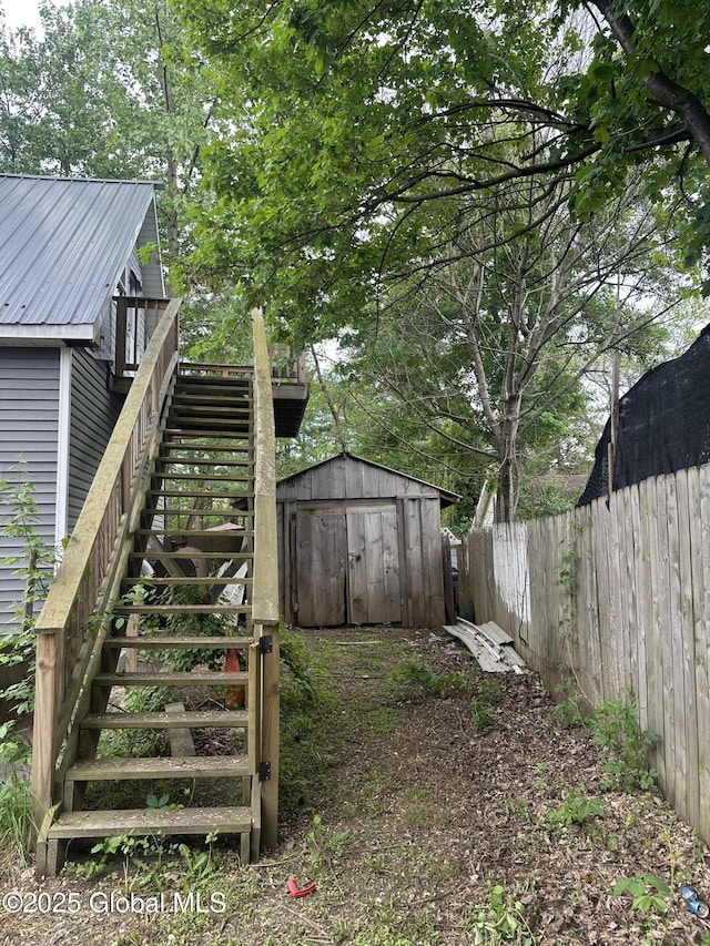 fenced backyard with stairs, a storage unit, and an outbuilding