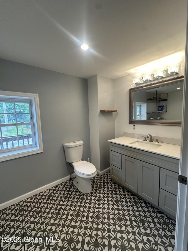 half bath featuring vanity, toilet, baseboards, and recessed lighting