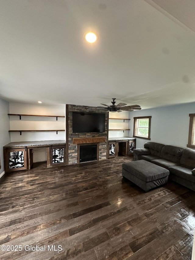 living area with dark wood-style floors, a stone fireplace, ceiling fan, and recessed lighting