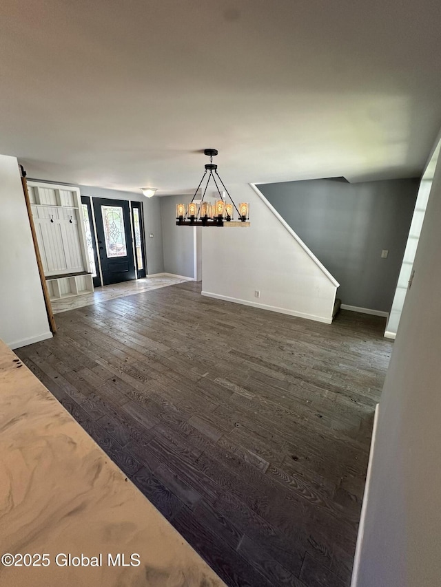 foyer entrance featuring a chandelier, baseboards, and dark wood finished floors
