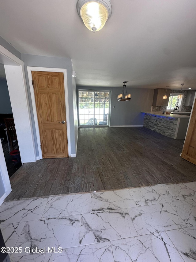 unfurnished living room featuring wood finished floors, a chandelier, and baseboards