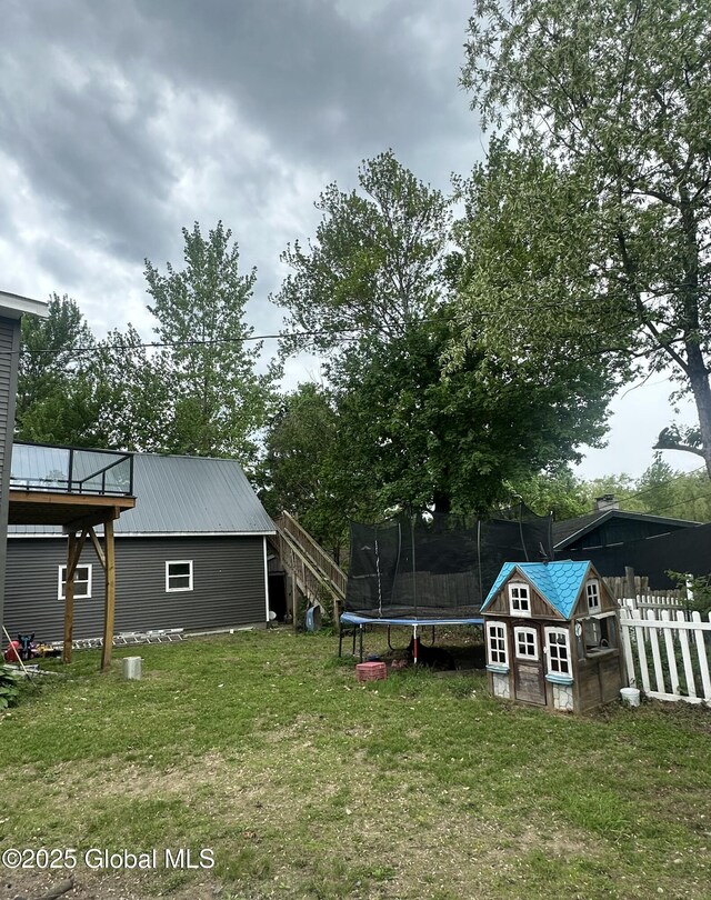 view of yard featuring a trampoline, an outbuilding, and a storage shed