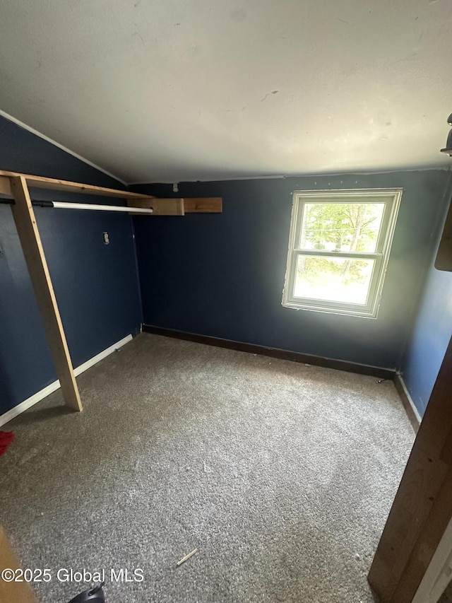 unfurnished bedroom with carpet, vaulted ceiling, and baseboards