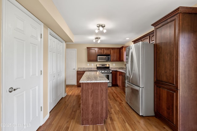 13 Peach Tree Ln, Wilton, NY 12831 - kitchen featuring appliances with stainless steel finishes, a center island, light wood-style floors, and light stone counters