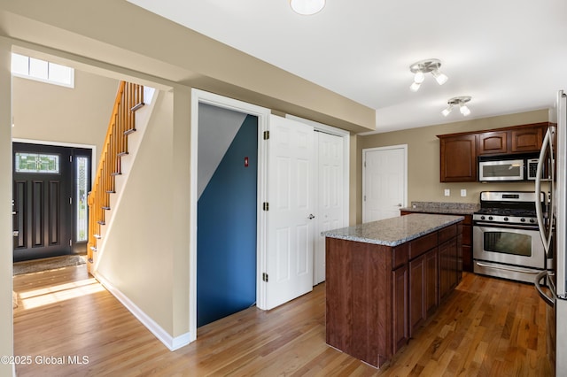 13 Peach Tree Ln, Wilton, NY 12831 - kitchen featuring appliances with stainless steel finishes, light wood-type flooring, a center island, light stone counters, and baseboards