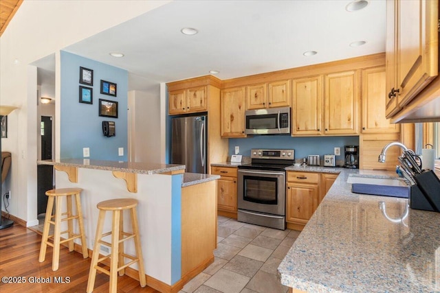 2158 State Route 29, Greenwich, NY 12834 - kitchen featuring stainless steel appliances, a sink, a kitchen bar, light stone countertops, and recessed lighting