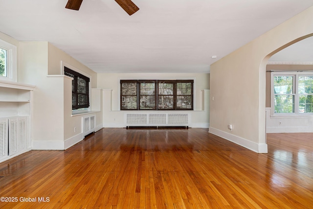 58 Old Loudon Rd, Colonie, NY 12110 - unfurnished living room with radiator, arched walkways, hardwood / wood-style flooring, ceiling fan, and baseboards