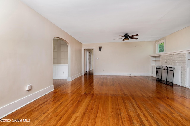58 Old Loudon Rd, Colonie, NY 12110 - unfurnished living room with arched walkways, ceiling fan, light wood-style flooring, a brick fireplace, and baseboards
