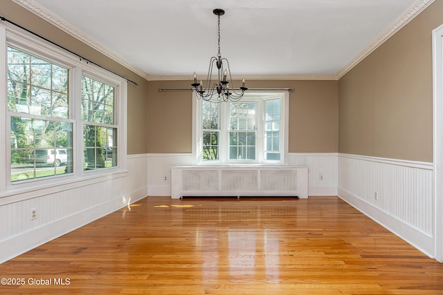 58 Old Loudon Rd, Colonie, NY 12110 - unfurnished dining area featuring radiator heating unit, a chandelier, plenty of natural light, light wood-type flooring, and a wainscoted wall