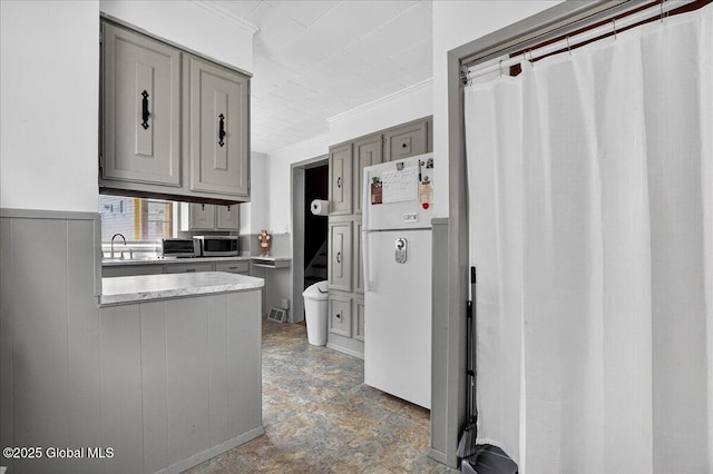 302 S William St, Johnstown, NY 12095 - kitchen with freestanding refrigerator, gray cabinetry, stainless steel microwave, light countertops, and ornamental molding