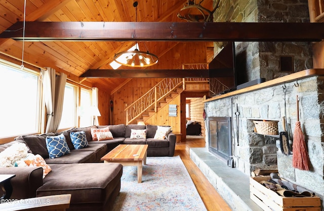745 Adirondack Rd, Schroon Lake, NY 12870 - living room featuring wood ceiling with exposed beams, wooden walls, wood finished floors, a stone fireplace, and stairs
