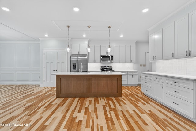 480 Selfridge Rd, Moreau, NY 12831 - kitchen featuring appliances with stainless steel finishes, decorative backsplash, light countertops, white cabinetry, and a center island with sink