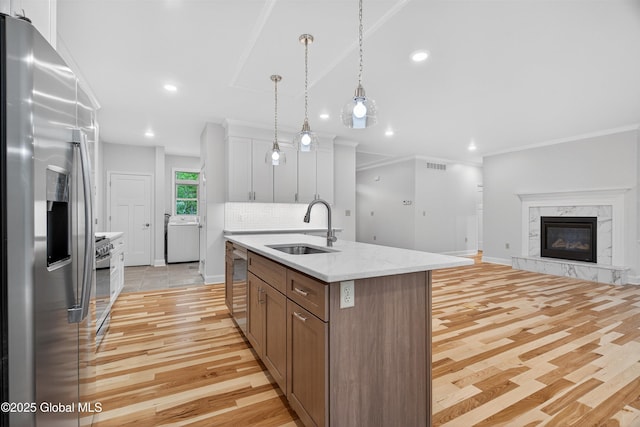 480 Selfridge Rd, Moreau, NY 12831 - kitchen featuring stainless steel appliances, washer / dryer, light wood-type flooring, a center island with sink, and pendant lighting