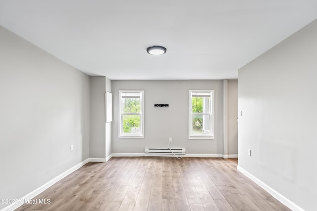 spare room with baseboard heating, wood finished floors, and baseboards