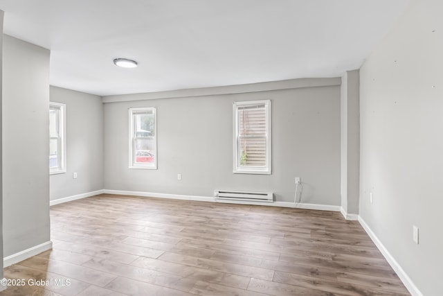 spare room with a baseboard radiator, wood finished floors, and baseboards