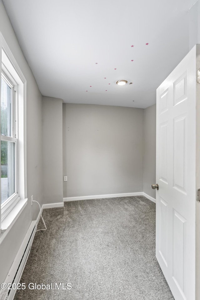 empty room featuring a baseboard radiator, carpet, and baseboards