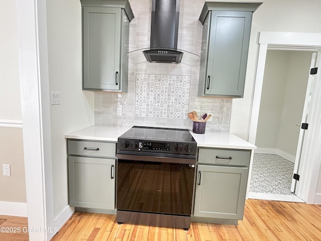 354 Mohawk Ave, Scotia, NY 12302 - kitchen with black range with electric cooktop, wall chimney range hood, gray cabinets, baseboards, and backsplash