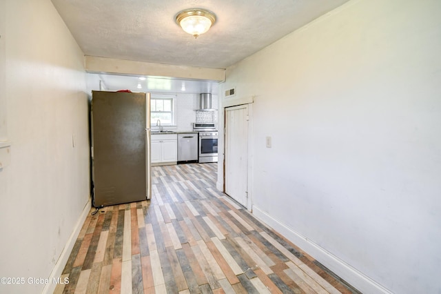 676 Stoner Trail Rd, Mohawk, NY 12068 - kitchen featuring appliances with stainless steel finishes, wall chimney exhaust hood, white cabinets, light wood-style flooring, and a sink