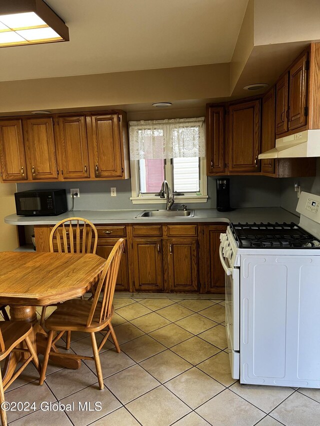 1643 Rugby Rd, Schenectady, NY 12309 - kitchen featuring white gas stove, under cabinet range hood, a sink, black microwave, and light tile patterned floors