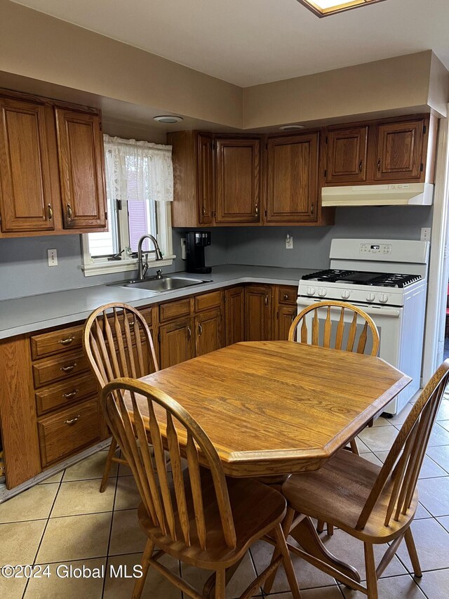 1643 Rugby Rd, Schenectady, NY 12309 - kitchen featuring a sink, under cabinet range hood, light tile patterned flooring, white gas range, and light countertops
