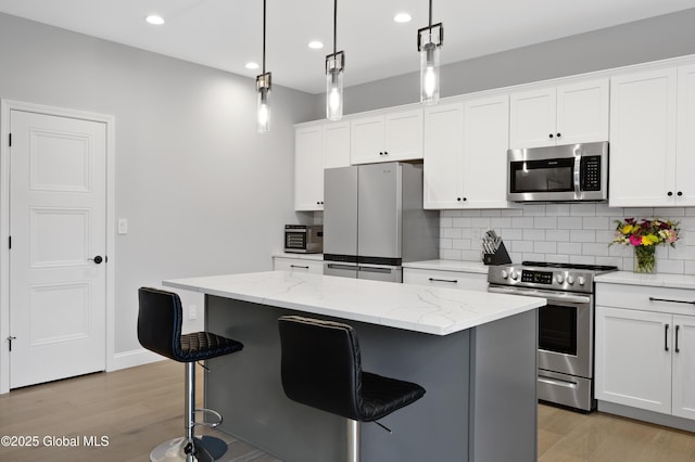 39 Berkeley Way, Wilton, NY 12866 - kitchen with appliances with stainless steel finishes, a kitchen bar, decorative backsplash, light wood-type flooring, and recessed lighting