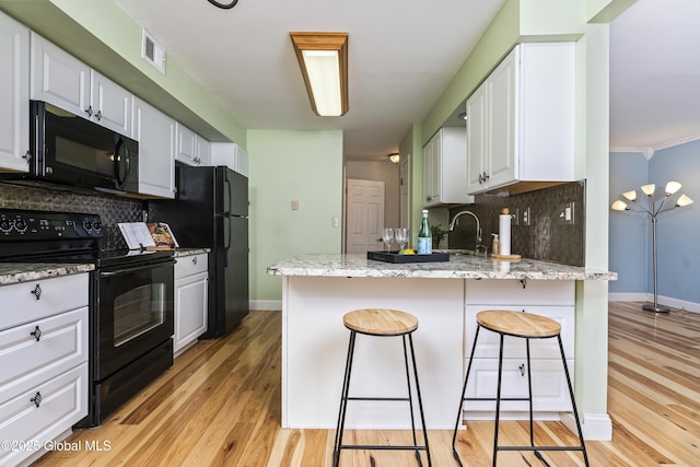 110 Deer Run Dr, Milton, NY 12020 - kitchen with black appliances, decorative backsplash, a peninsula, and white cabinetry