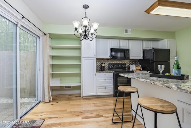 110 Deer Run Dr, Milton, NY 12020 - kitchen with black appliances, a chandelier, light wood-type flooring, tasteful backsplash, and light stone countertops