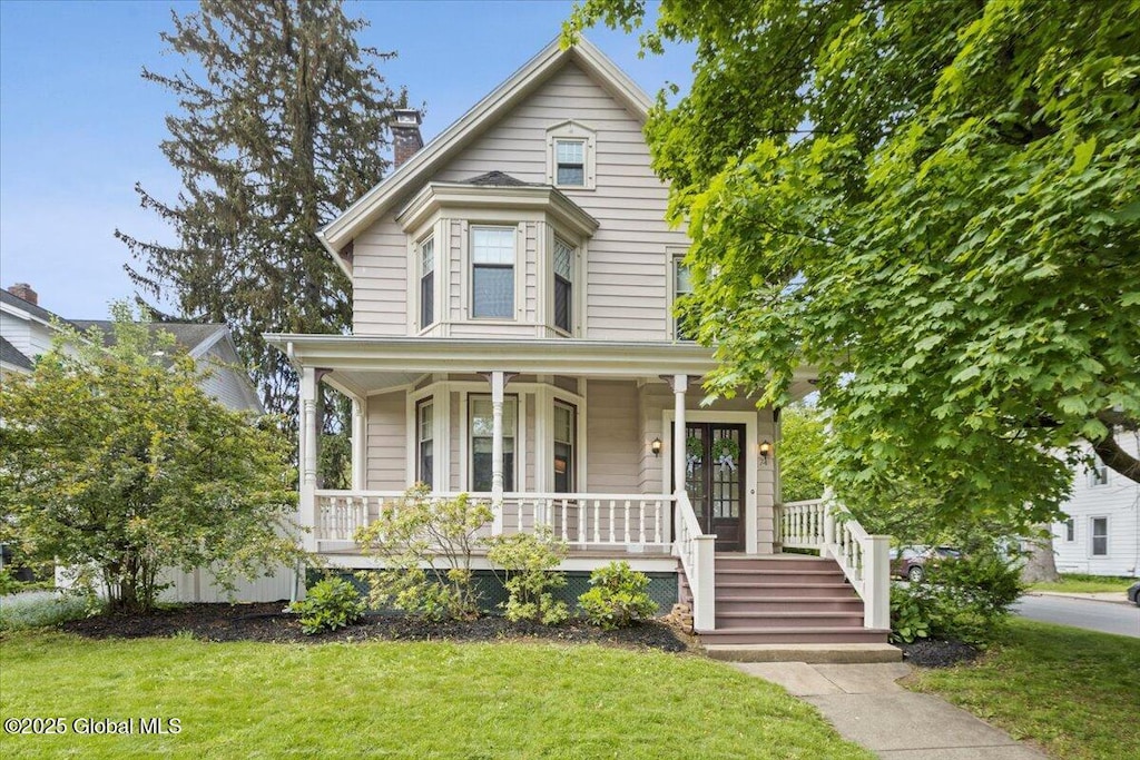 74 Pinewoods Ave, Troy, NY 12180 - view of front of home featuring covered porch, a front yard, and a chimney