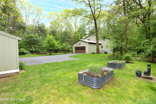 124 Edie Rd, Wilton, NY 12866 - view of green lawn with an outbuilding, asphalt driveway, a garage, and a vegetable garden