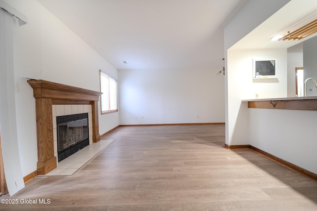 1976 Curry Rd Unit E-136, Schenectady, NY 12303 - unfurnished living room with light wood finished floors, a tiled fireplace, and baseboards