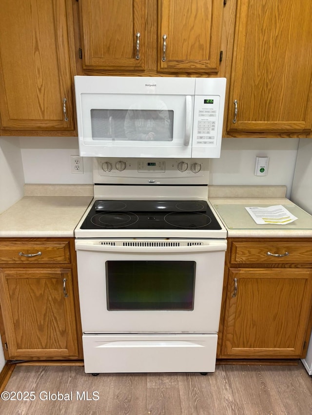 1976 Curry Rd Unit E-136, Schenectady, NY 12303 - kitchen featuring white appliances, wood finished floors, light countertops, and brown cabinets