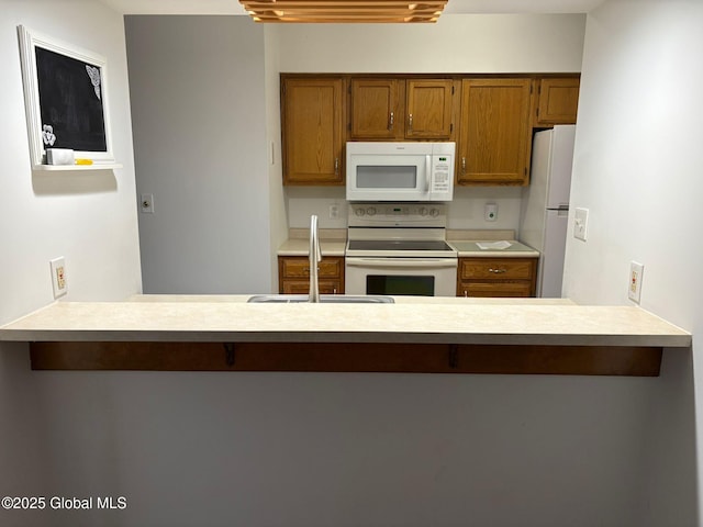 1976 Curry Rd Unit E-136, Schenectady, NY 12303 - kitchen with white appliances, a sink, a peninsula, and brown cabinets