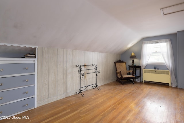 184 Main St, South Glens Falls, NY 12803 - living area featuring radiator, wood finished floors, vaulted ceiling, and wooden walls