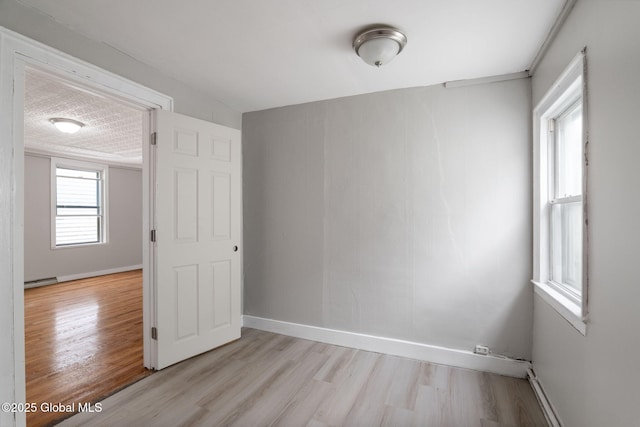 2127 2nd Ave, Watervliet, NY 12189 - empty room with light wood-style floors, baseboards, and a baseboard heating unit